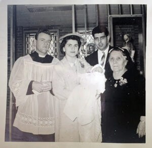 Questa foto ritrae una famiglia italiana emigrata negli Stati Uniti d’America e inviata a Conflenti, paese calabrese in provincia di Catanzaro, come ricordo di un battesimo. La madre regge in braccio la bambina vestita in abito rituale da battesimo con alla sua destra il prete e alla sua sinistra la madre, dietro posa il marito.