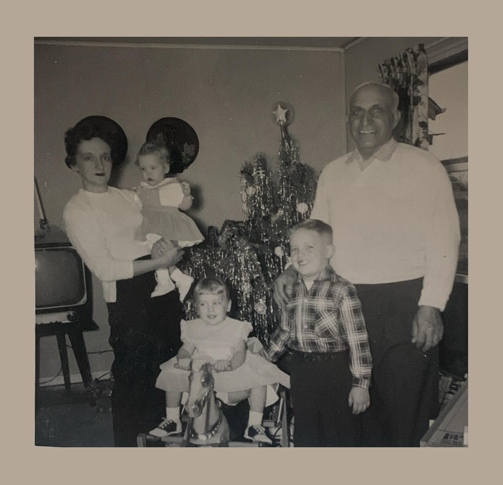 Questa foto ritrae un donna conflentese emigrata negli Stati Uniti d’America e inviata a Conflenti, paese calabrese in provincia di Catanzaro, come ricordo di un Natale trascorso insieme. La famiglia, sorridente, è in posa d’avanti l’albero di natale.